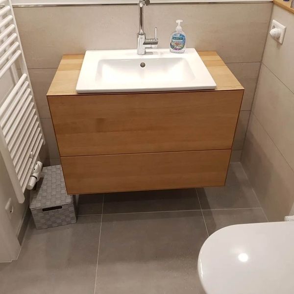 Blick auf ein Gäste-WC mit Waschbeckenunterschrank aus Holz